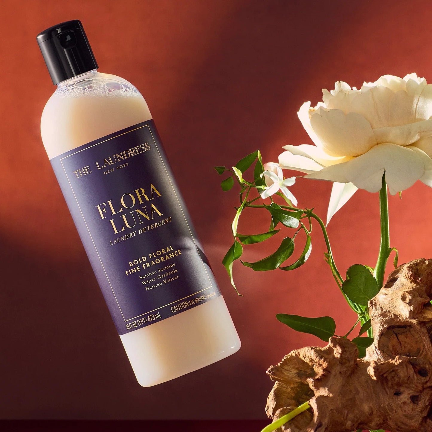 Bottle of Flora Luna detergent with flowers and branches on a burgundy background