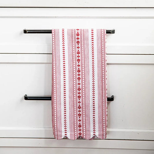 Red and white pattern-striped tea towel hanging from the handle of kitchen cabinet drawers