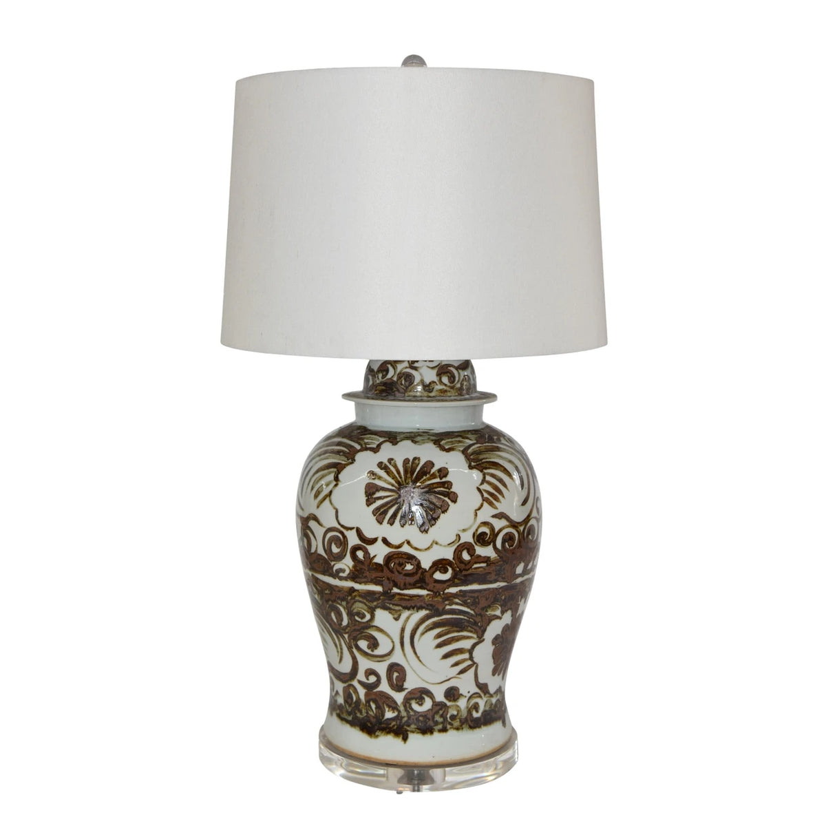 A table lamp with a white drum shade and a glossy white ceramic base decorated with brown floral and scroll patterns.