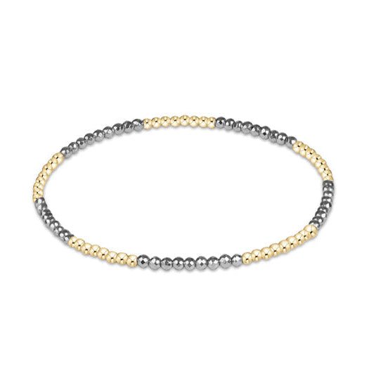 A delicate beaded bracelet with alternating strands of polished silver and yellow gold beads, arranged in a horizontal oval on a solid white background.