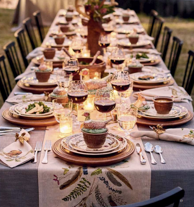 Elegant outdoor dinner table setting with wine glasses, plates, and decorative elements.