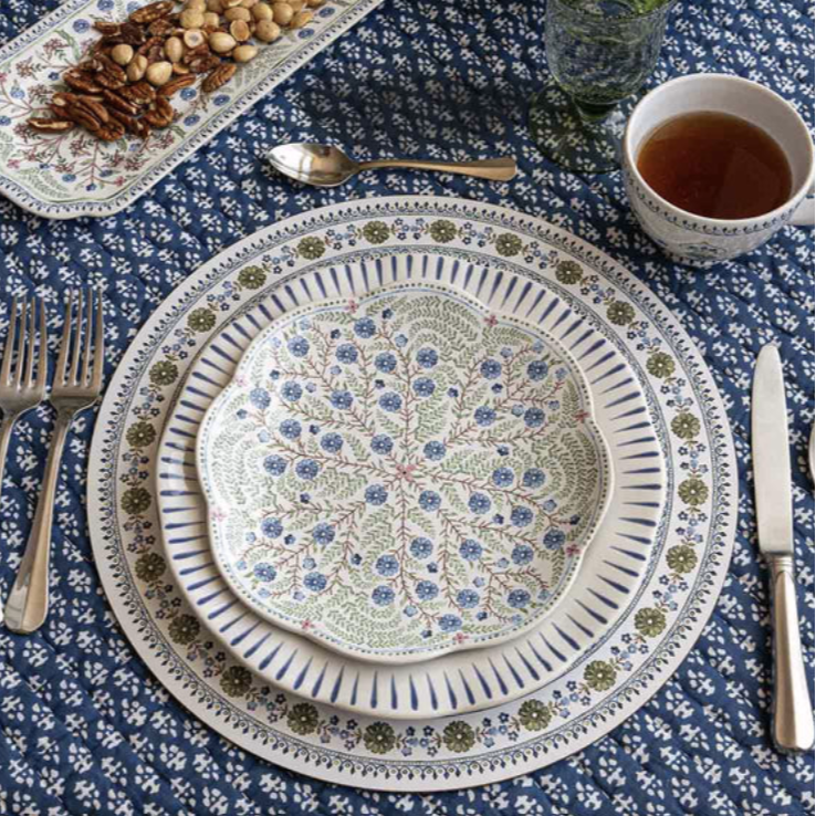 Decorative salad plate with floral pattern on a mixed table setting with other patterns, cutlery, and hot tea.