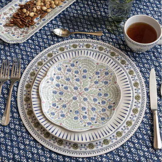 Decorative salad plate with floral pattern on a mixed table setting with other patterns, cutlery, and hot tea.