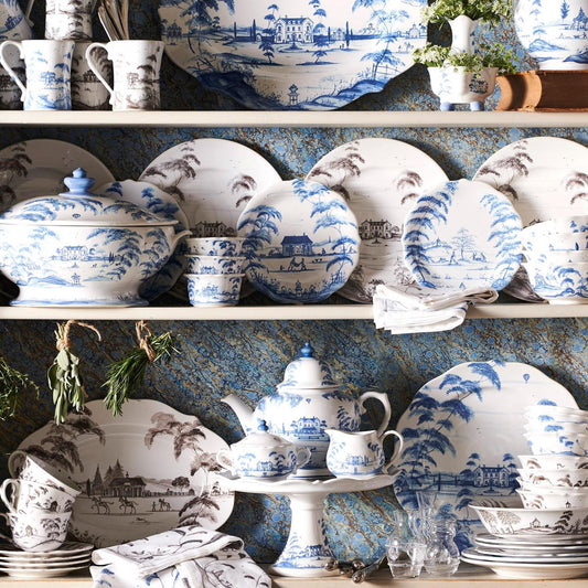 A collection of delft blue ramekins and dinnerware with white and blue floral patterns, displayed on a shelf against a blue textured background.
