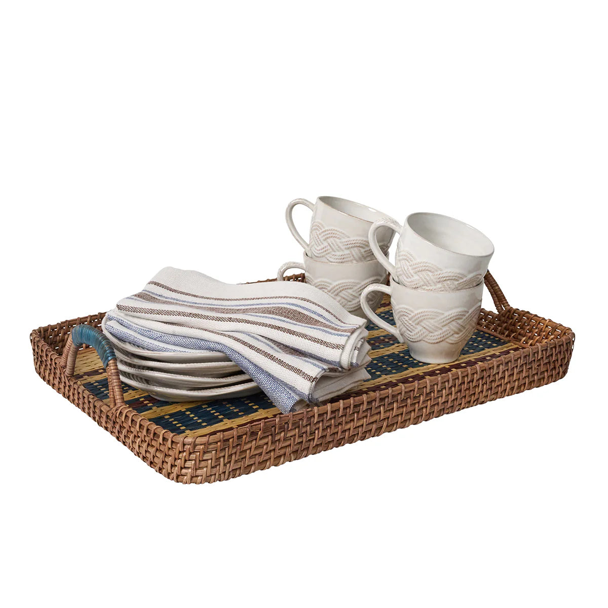 Set of ceramic mugs and striped napkins on a woven tray with a white background