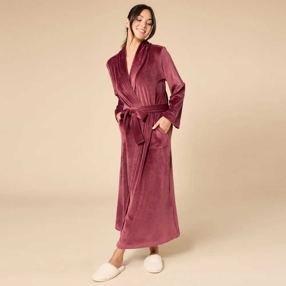 Woman wearing a velvety burgundy robe on a beige background