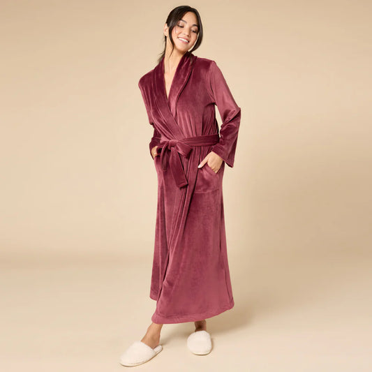 Woman wearing a velvety burgundy robe on a beige background