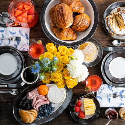 Arial view of a dessert table with pastries, fruit, and flowers on a wooden table
