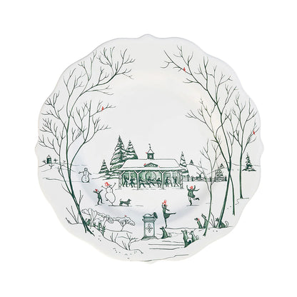Decorative white plate with green toile winter scene design featuring trees, a stable, and people in a snowy landscape.
