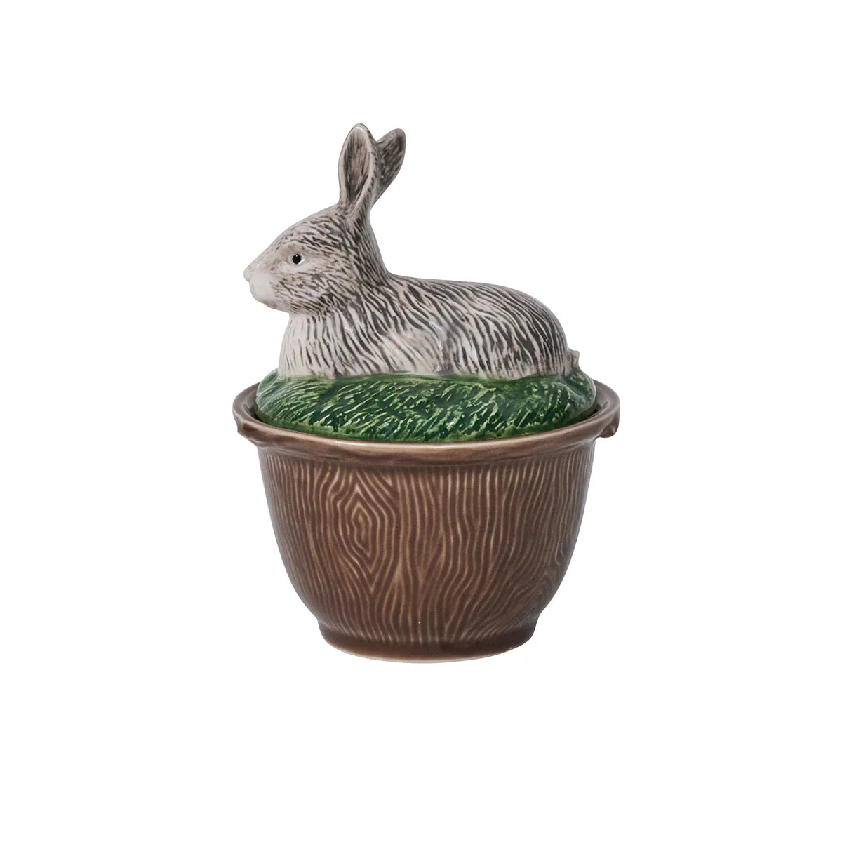 A brown-ceramic, faux bois bowl with a lid with a rabbit laying in grass.