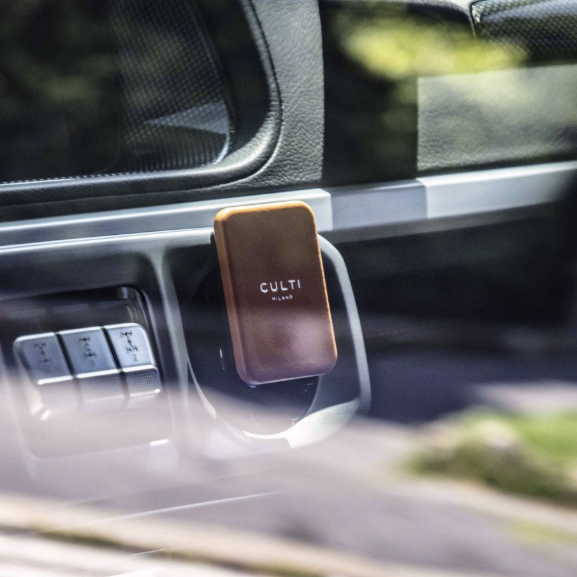 A through-the-mirror view of an orange clip-on car diffuser on an air vent in a luxurious car