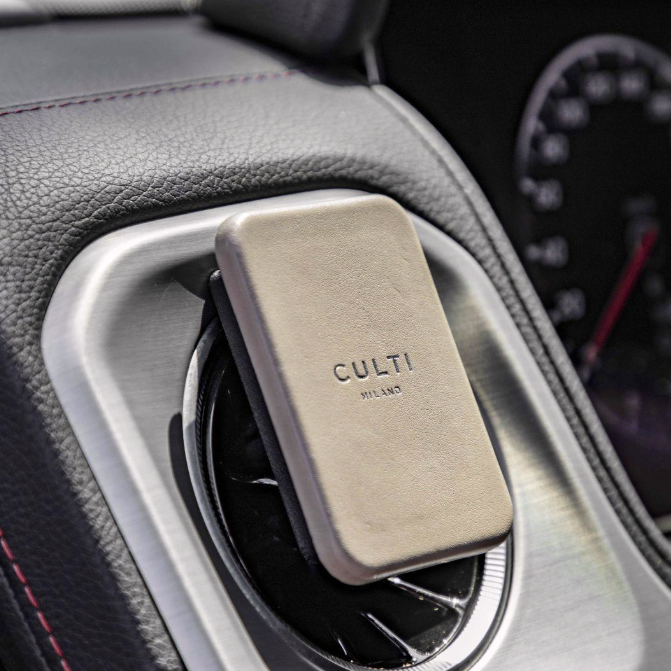 A taupe clip-on car diffuser on an air vent in a luxurious car