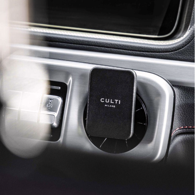 A through-the-mirror view of A black clip-on car diffuser on an air vent in a luxurious car