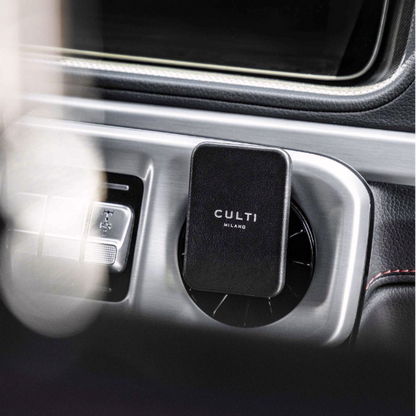 A through-the-mirror view of A black clip-on car diffuser on an air vent in a luxurious car