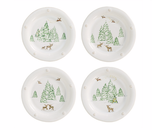 Four white cocktail plates with Christmas tree and reindeer designs on a white background
