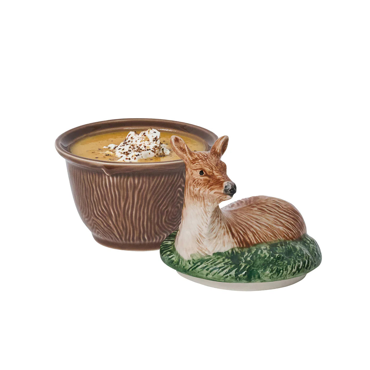 A brown-ceramic, faux bois bowl with soup positioned next to a lid with a deer laying in grass.