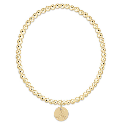 Gold beaded bracelet with a round disc charm on a white background