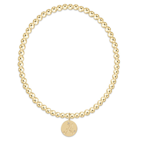 Gold beaded bracelet with a round disc charm on a white background