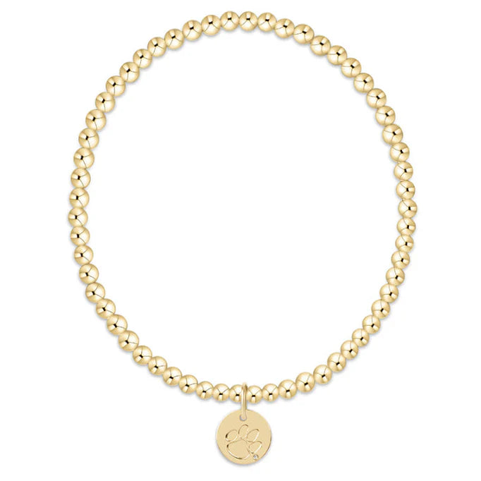 Gold beaded bracelet with a round disc charm on a white background