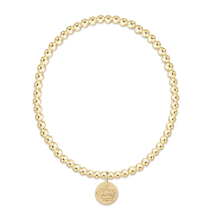 Gold beaded bracelet with a round disc charm on a white background