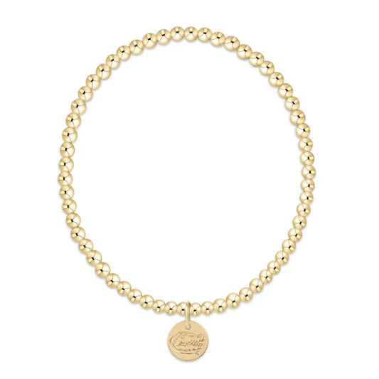 Gold beaded bracelet with a round disc charm on a white background