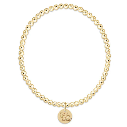 Gold beaded bracelet with a round tag on a white background