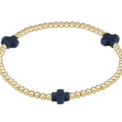 Gold beaded bracelet with navy blue cross-shaped beads on a white background