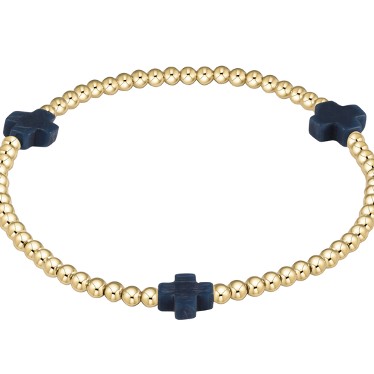 Gold beaded bracelet with navy blue cross-shaped beads on a white background