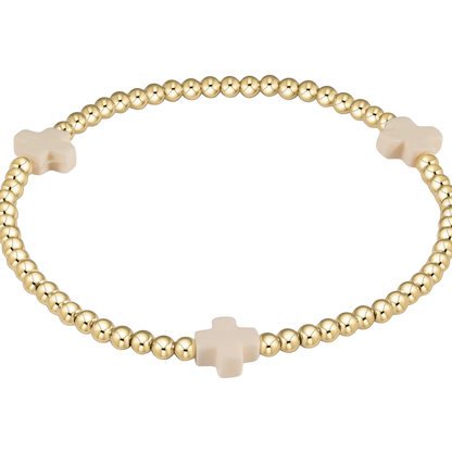 Gold beaded bracelet with beige cross beads on a white background