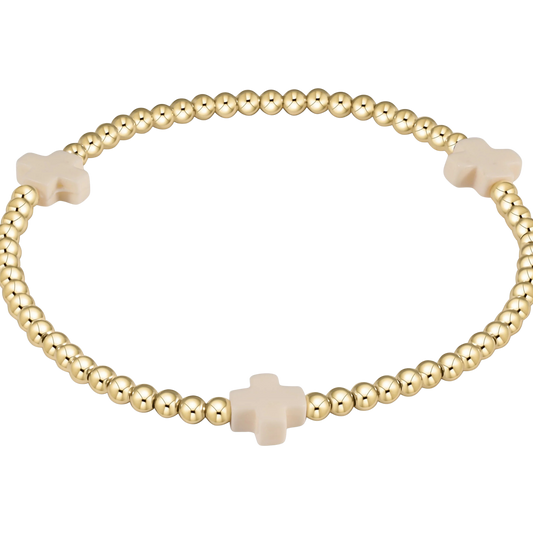 Gold beaded bracelet with beige cross beads on a white background