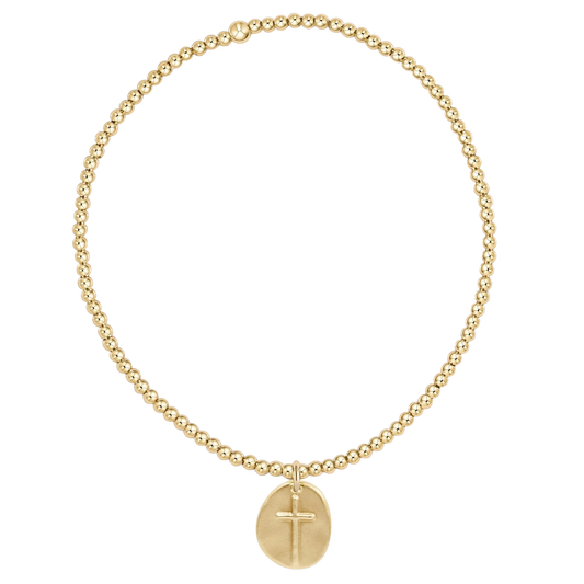 Gold bracelet with a cross pendant on a white background