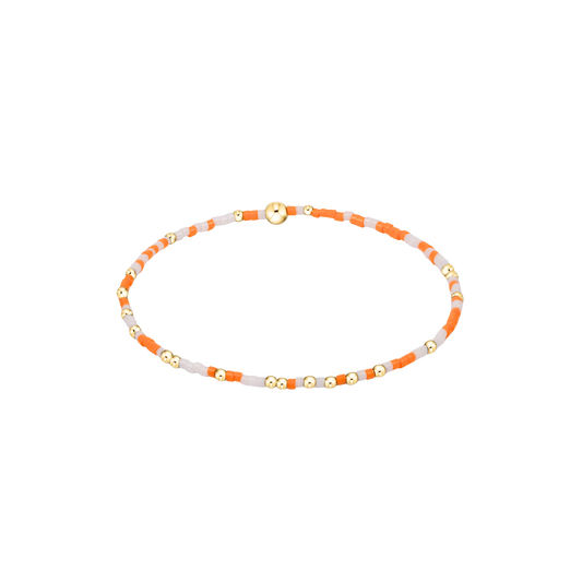 Bracelet with orange, white, and gold beads on a white background