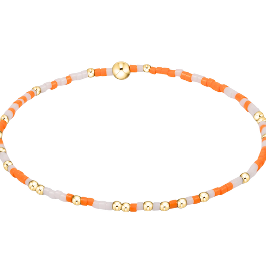 Bracelet with orange, white, and gold beads on a white background