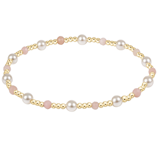 Pearl and gold and pink beaded bracelet on a white background