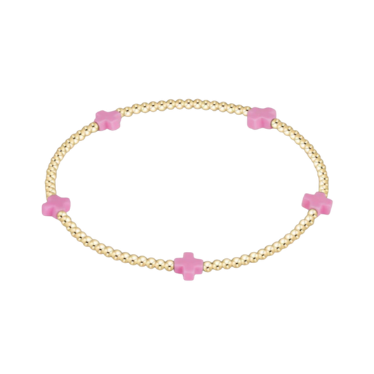 Gold bracelet with pink cross-shaped beads on a white background