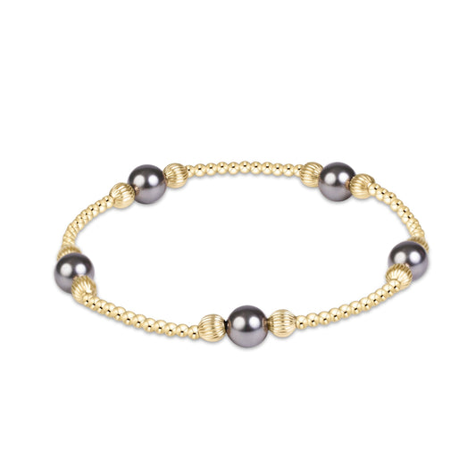 A gold beaded bracelet featuring five dark gray freshwater pearls and textured gold spacer beads, displayed on a clean white background.