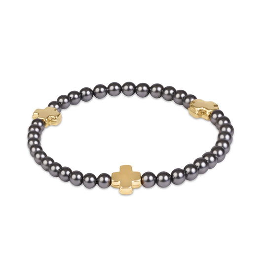 A beaded bracelet featuring dark gray pearls and polished gold-tone cross-shaped charms, displayed on a clean white background.