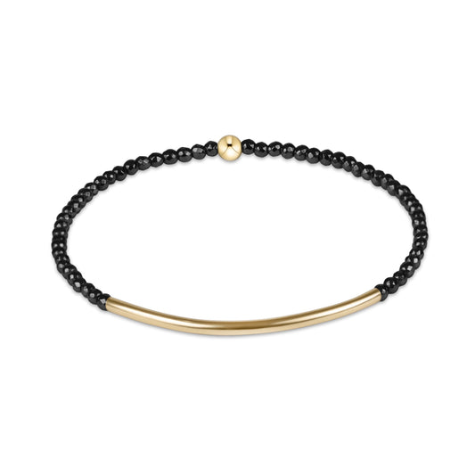 A delicate black beaded bracelet with a polished gold bar and a small gold accent bead, displayed on a clean white background.