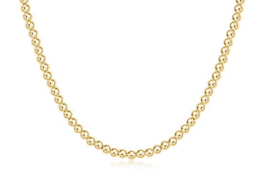 A delicate gold ball chain necklace displayed in a curved U-shape against a clean white background.