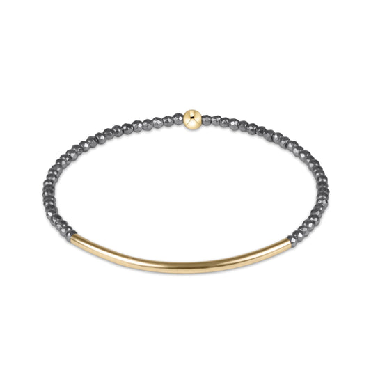 A delicate gold and dark gray beaded bracelet on a clean white background.