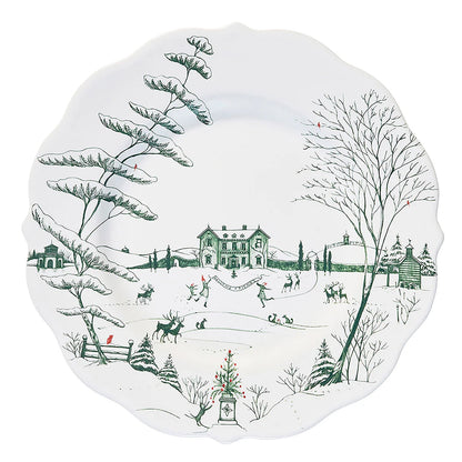 Decorative white plate with green toile winter scene design featuring trees, houses, and people.