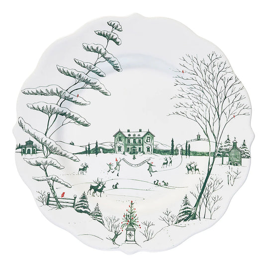 Decorative white plate with green toile winter scene design featuring trees, houses, and people.