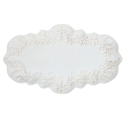 An oval white ceramic serving platter with a scalloped edge and raised floral lace-like pattern around the border, shown on a plain white background.