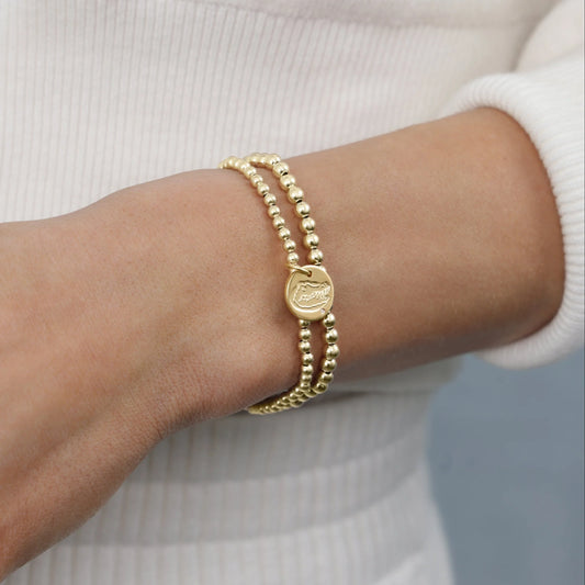 Gold bracelet on a wrist with a plain background