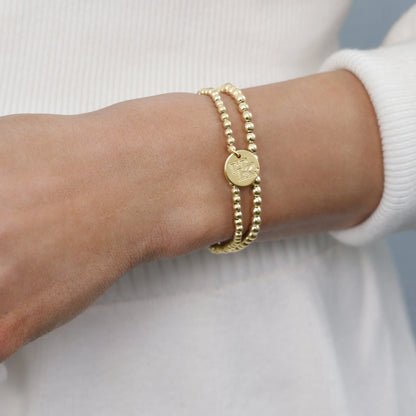 Gold bracelet on a wrist with a plain background