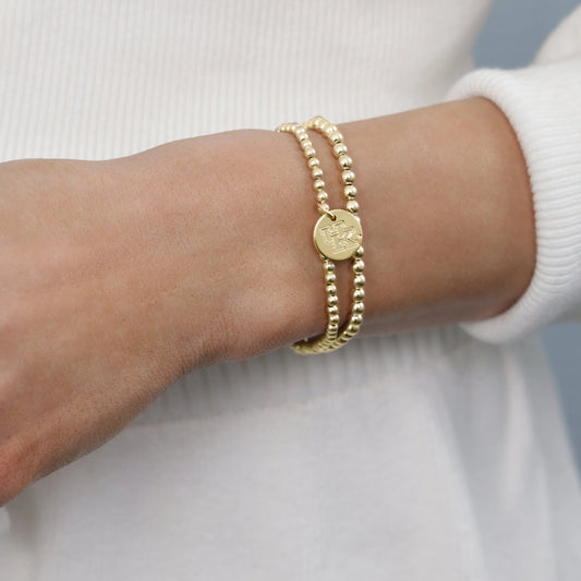 Gold bracelet on a wrist with a plain background