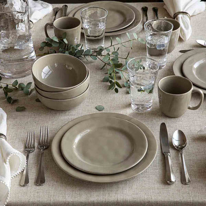Elegant table setting with beige plates, cups, and silverware on a textured tablecloth.