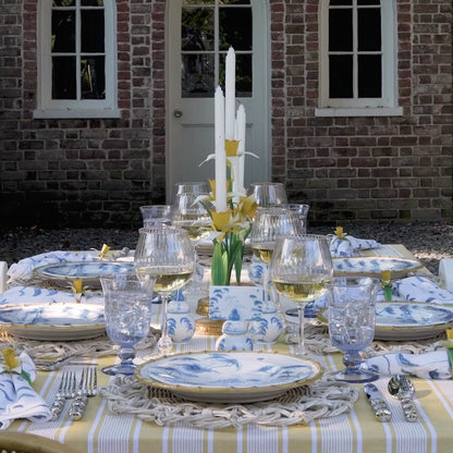 A video of an intricate table set with bamboo and blue toile dishes and decorate with yellow linens and centerpieces for a maximalist, happy look