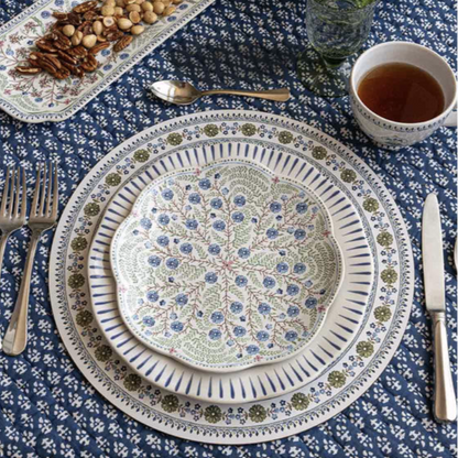 Decorative salad plate with floral pattern on a mixed table setting with other patterns, cutlery, and hot tea.