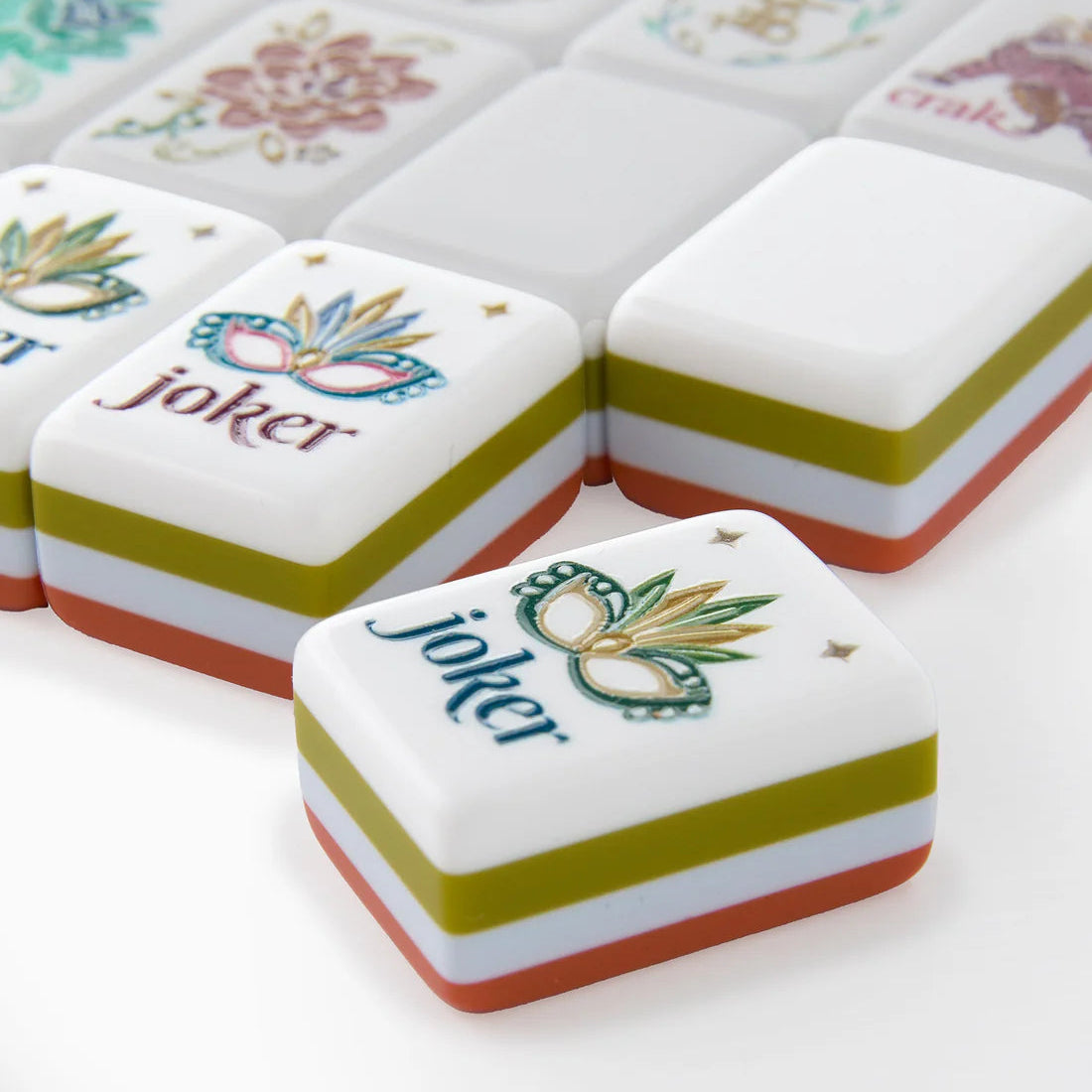 Decorative Mahjong tiles with a white tile face, with an olive green, powder blue, and burnt orange-brown strip around the sides and bottom of each tile.